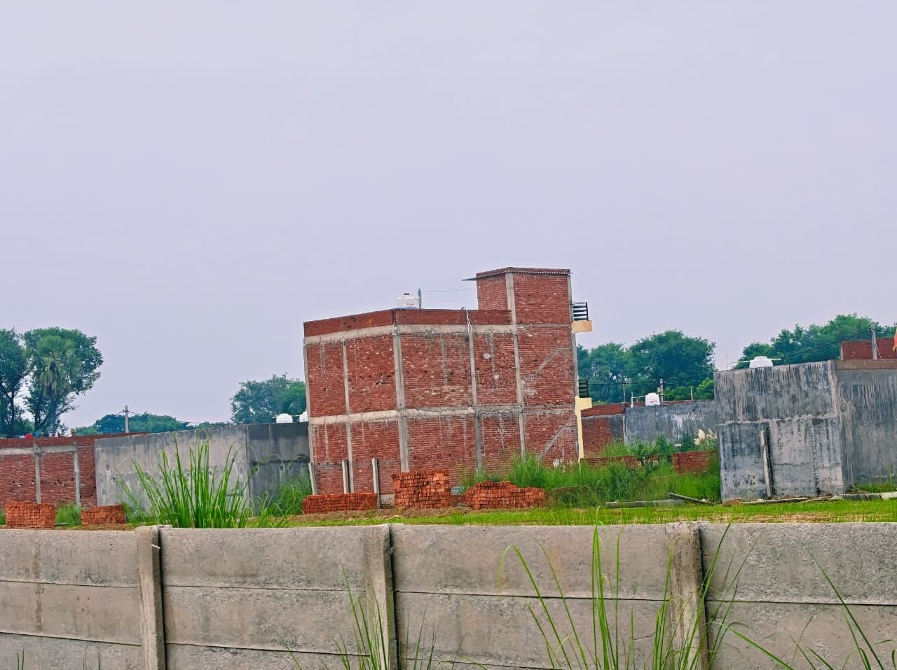 Concrete boundary wall and demarcated plots in Dauwa Green City